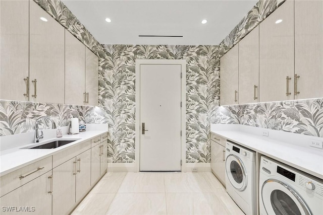 laundry room featuring washing machine and clothes dryer, cabinet space, a sink, wallpapered walls, and baseboards
