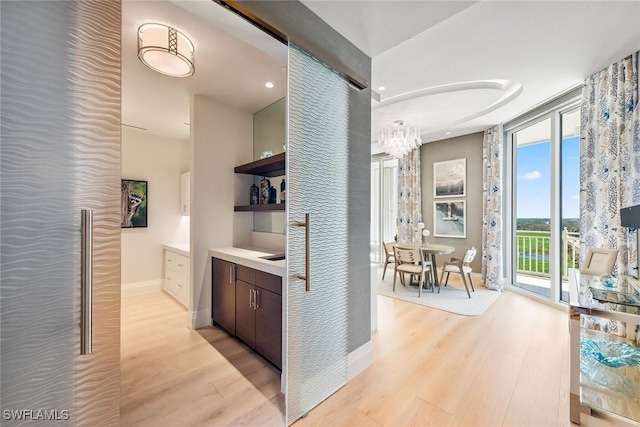 hall featuring light wood-style flooring and baseboards