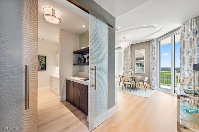 corridor featuring recessed lighting, baseboards, a chandelier, and light wood-style flooring