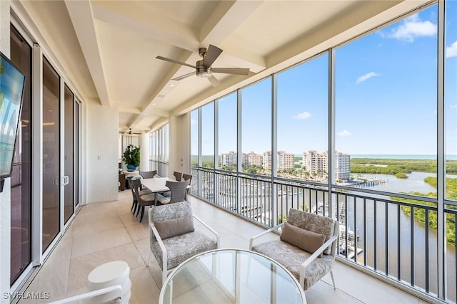 sunroom with a view of city, a water view, a wealth of natural light, and a ceiling fan