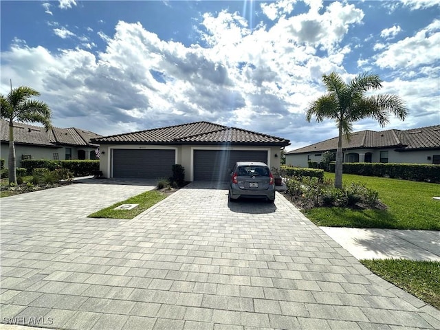 view of front of home featuring decorative driveway, stucco siding, an attached garage, a tiled roof, and a front lawn