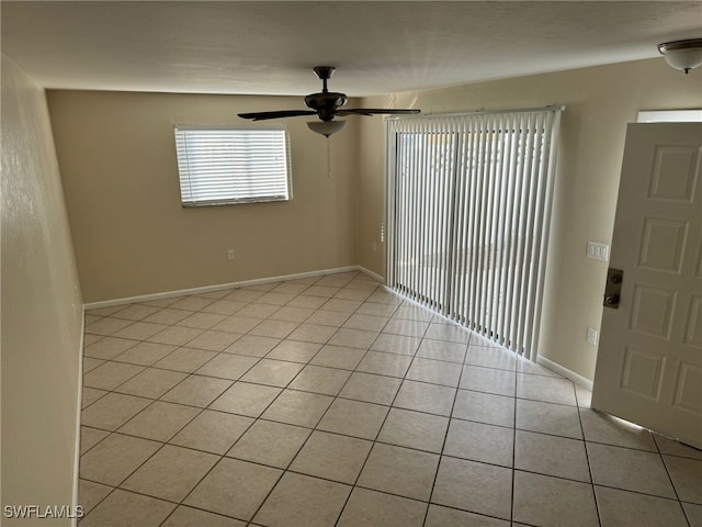 empty room with light tile patterned floors, a ceiling fan, and baseboards