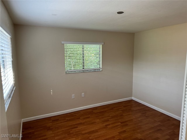 spare room featuring baseboards and dark wood finished floors