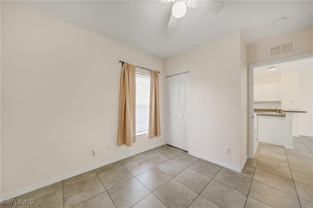 unfurnished bedroom with light tile patterned floors, a closet, visible vents, ceiling fan, and baseboards