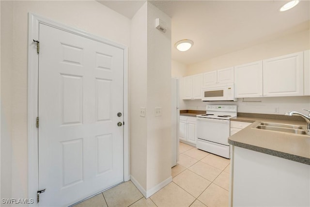 kitchen with white appliances, light tile patterned floors, baseboards, white cabinets, and a sink