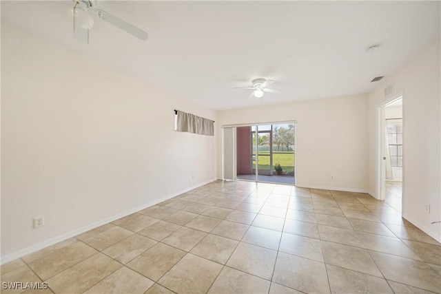 empty room with light tile patterned flooring, ceiling fan, visible vents, and baseboards