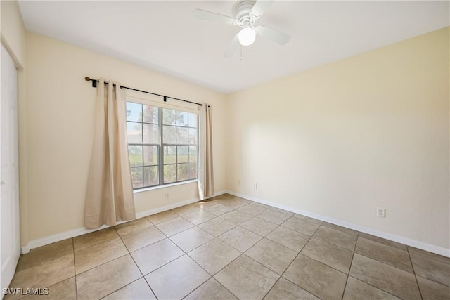 empty room with light tile patterned floors, ceiling fan, and baseboards