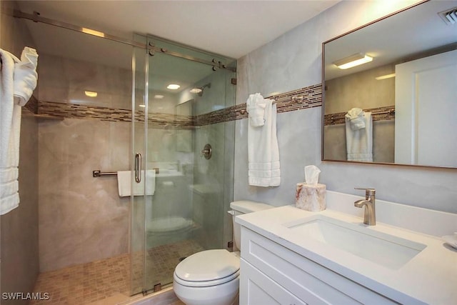 bathroom with a stall shower, vanity, and toilet