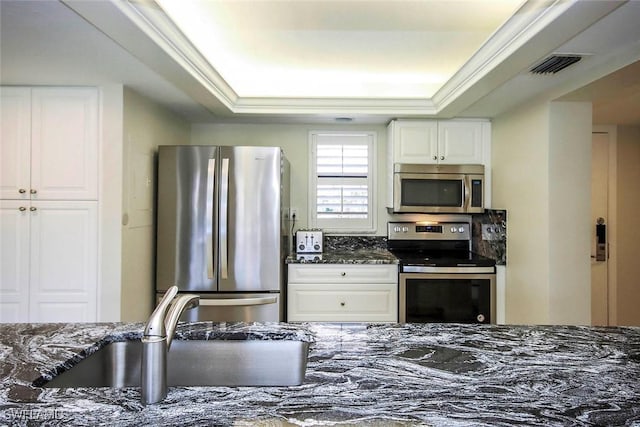 kitchen with a tray ceiling, appliances with stainless steel finishes, visible vents, and white cabinets