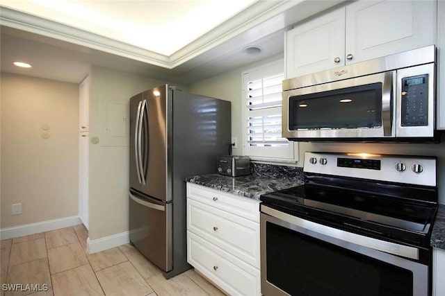 kitchen featuring stainless steel appliances, dark stone counters, white cabinets, and baseboards