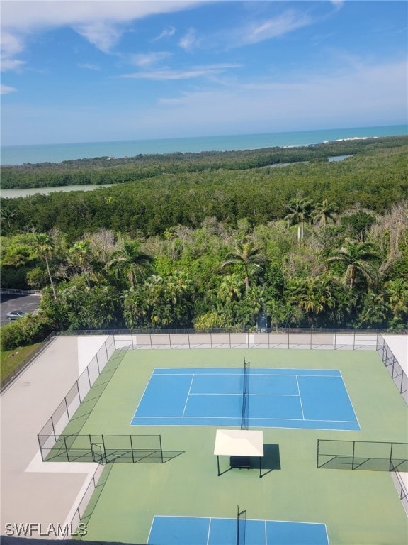 view of tennis court with a water view and fence