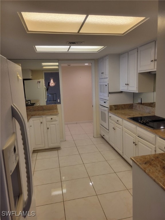 kitchen featuring white appliances, visible vents, light tile patterned floors, and white cabinetry