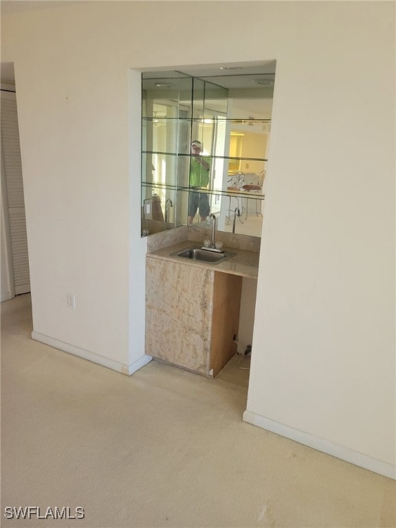 bar with wet bar, light carpet, a sink, and baseboards