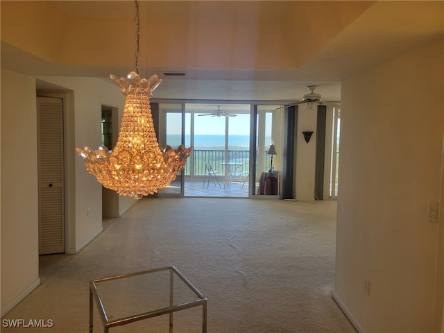 interior space with ceiling fan with notable chandelier, carpet floors, visible vents, and baseboards