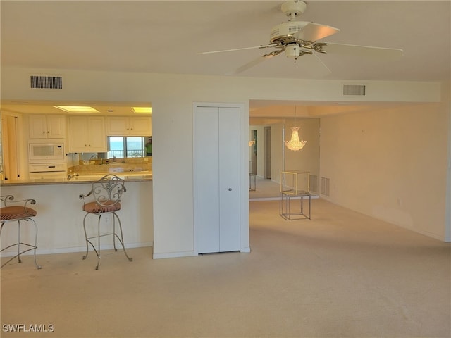 interior space featuring white microwave, a breakfast bar area, visible vents, and light colored carpet