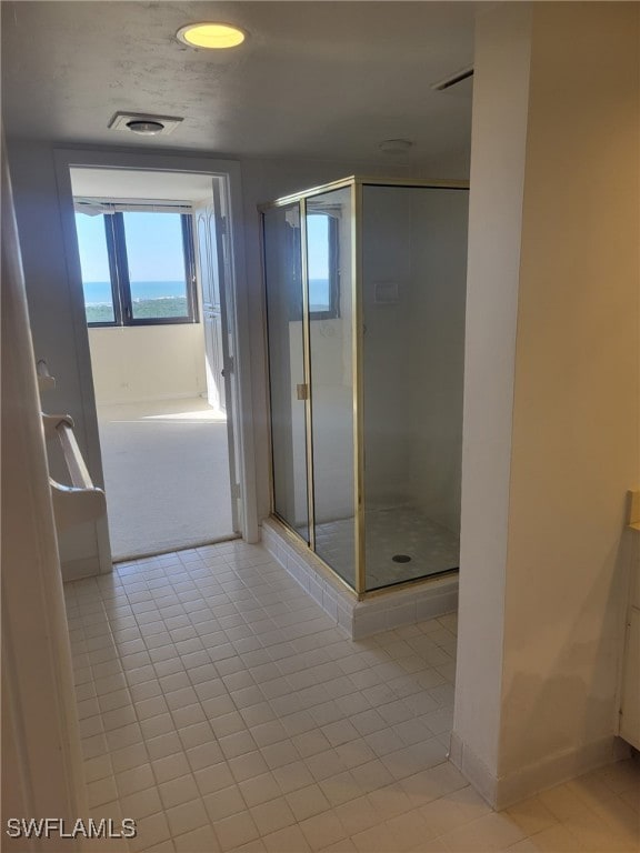 bathroom with a stall shower, tile patterned flooring, visible vents, and baseboards