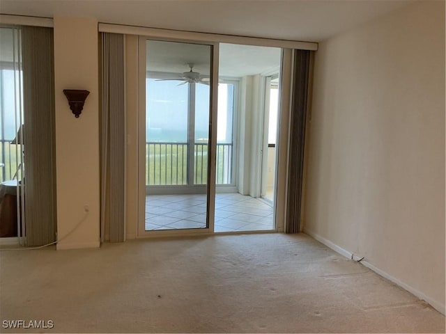 unfurnished room with a ceiling fan, carpet, floor to ceiling windows, and baseboards