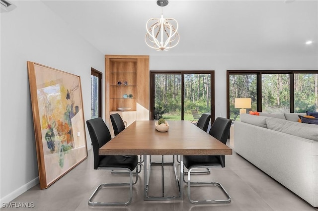 dining area featuring concrete flooring, baseboards, and an inviting chandelier