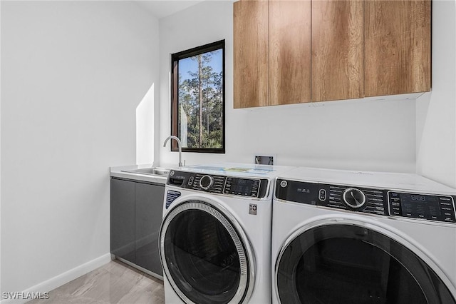 laundry area featuring washer and clothes dryer, a sink, cabinet space, and baseboards