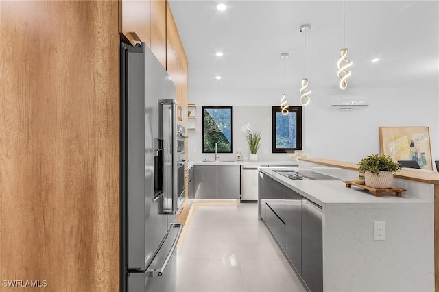 kitchen with pendant lighting, stainless steel appliances, light countertops, a sink, and modern cabinets