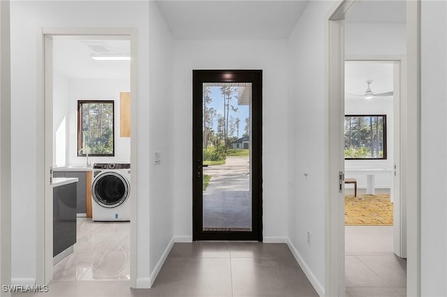 doorway to outside featuring washer / clothes dryer, a sink, and baseboards