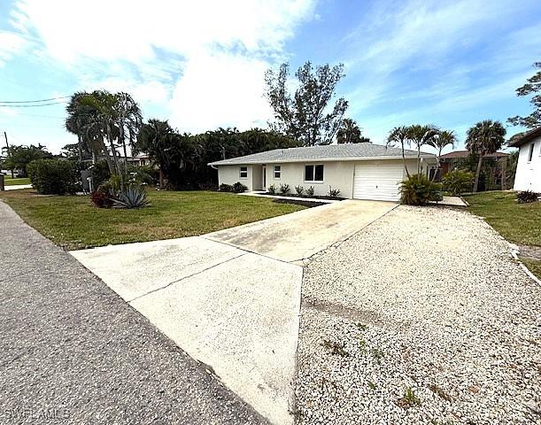 single story home with an attached garage, concrete driveway, and a front yard