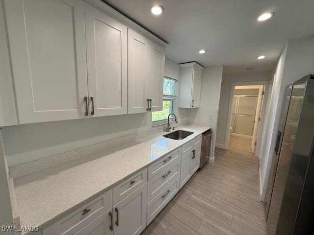 kitchen with white cabinetry, stainless steel appliances, a sink, and recessed lighting