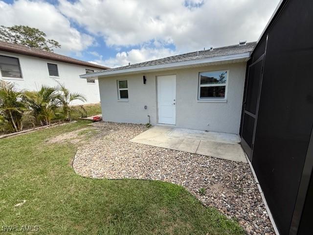 rear view of house with stucco siding, a patio, and a yard