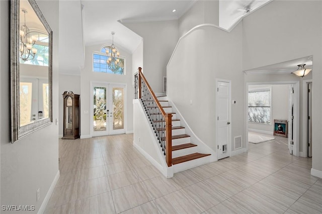 foyer entrance featuring a towering ceiling, stairway, crown molding, french doors, and a notable chandelier