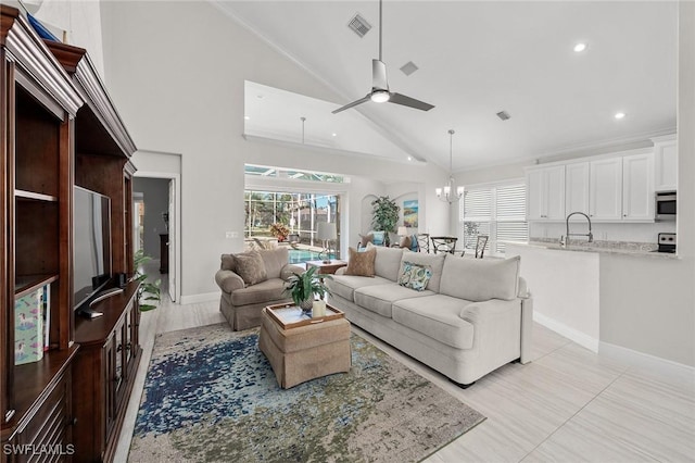 living area featuring a wealth of natural light, visible vents, and ceiling fan with notable chandelier