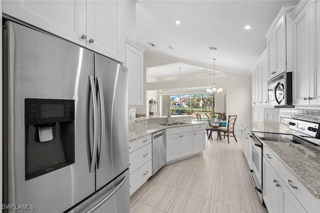 kitchen with white cabinets, vaulted ceiling, stainless steel appliances, a chandelier, and backsplash