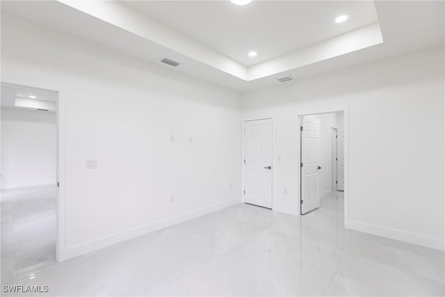 empty room with baseboards, visible vents, a tray ceiling, and recessed lighting