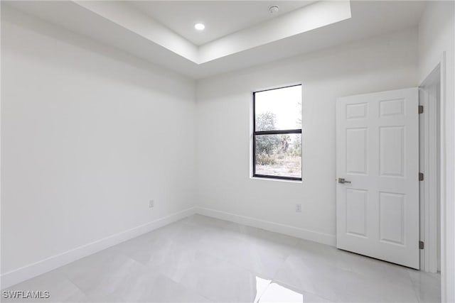 spare room featuring a tray ceiling, baseboards, and recessed lighting