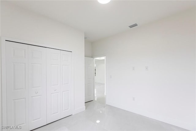 unfurnished bedroom with a closet, visible vents, and baseboards