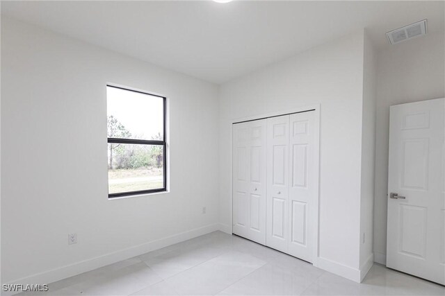 unfurnished bedroom with a closet, visible vents, and baseboards