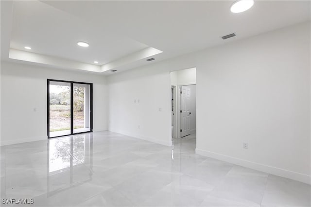 spare room featuring a tray ceiling, visible vents, baseboards, and recessed lighting