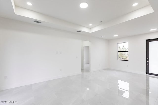 unfurnished room with baseboards, a raised ceiling, visible vents, and recessed lighting