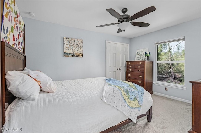 bedroom with a closet, light carpet, ceiling fan, and baseboards