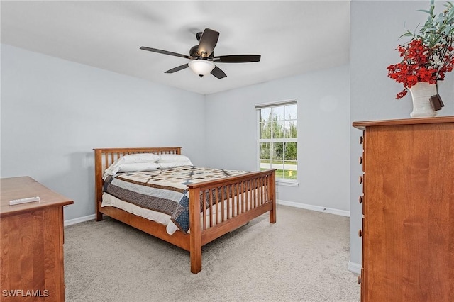 bedroom featuring light carpet, a ceiling fan, and baseboards