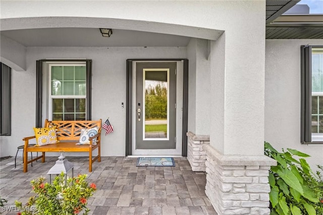 entrance to property featuring a porch and stucco siding