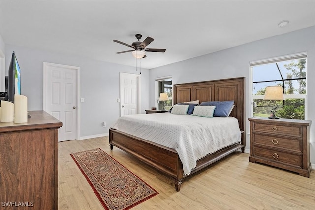 bedroom with light wood-type flooring, multiple windows, ceiling fan, and baseboards