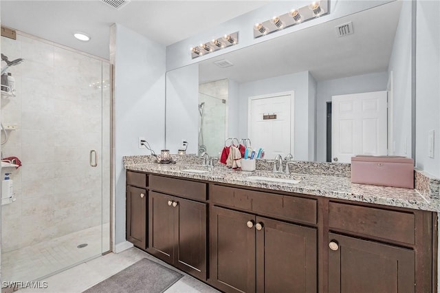 full bath with double vanity, a shower stall, visible vents, and a sink