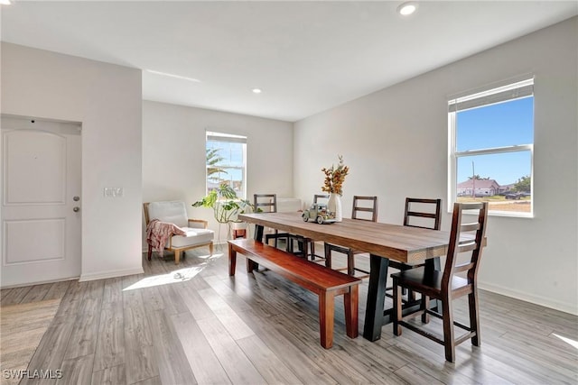 dining space featuring light wood-type flooring, a healthy amount of sunlight, and baseboards