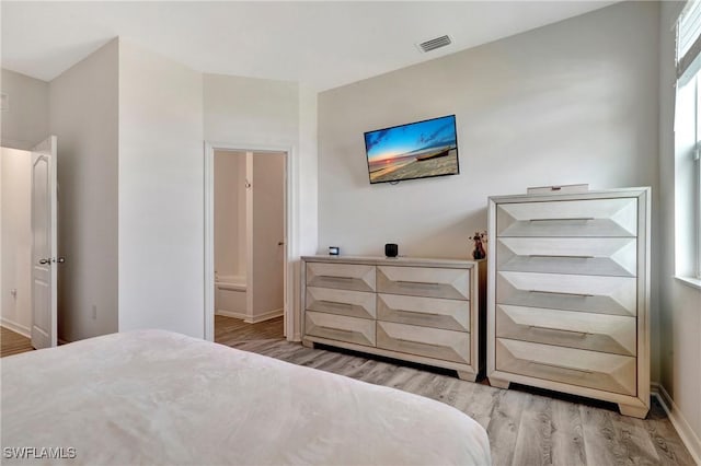 bedroom featuring baseboards, connected bathroom, visible vents, and light wood-style floors