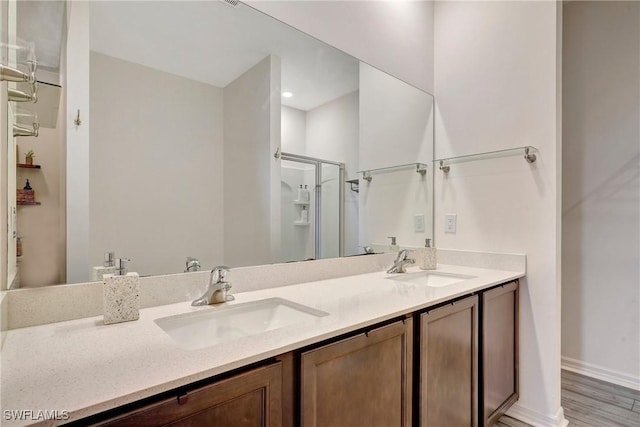 full bath featuring double vanity, wood finished floors, a sink, and a shower stall