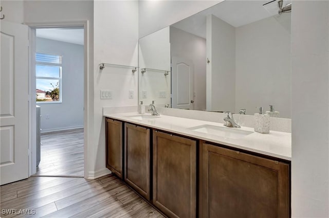 bathroom with double vanity, a sink, baseboards, and wood finished floors