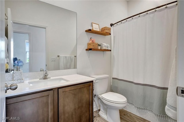 bathroom featuring toilet, a shower with shower curtain, wood finished floors, and vanity