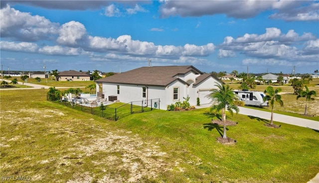 view of property exterior featuring a garage, fence, concrete driveway, a lawn, and a residential view