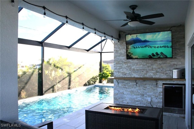 pool featuring glass enclosure, an outdoor fire pit, a patio, and a ceiling fan