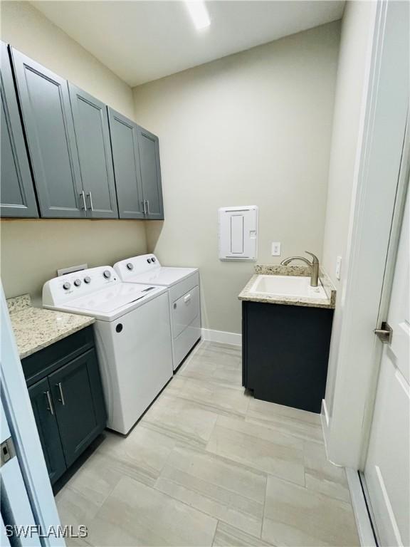 washroom featuring cabinet space, a sink, baseboards, and separate washer and dryer